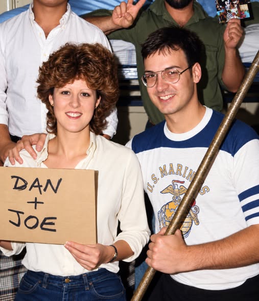 Doug Mastriano wears a U.S. Marines shirt alongside his wife, Rebbie Mastriano, who holds up a cardboard sign reading "DAN + JOE."